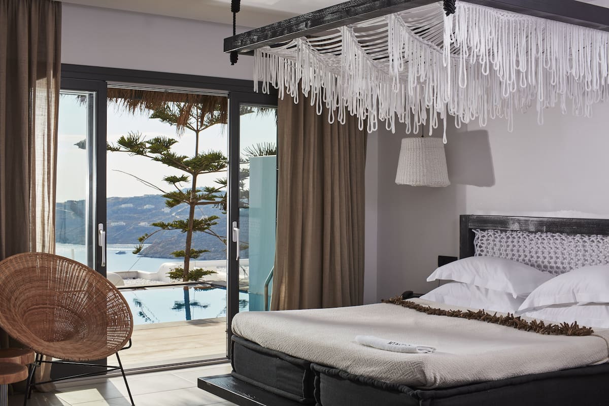 A bedroom with a bed, a chair, a view of a pool, and a balcony.