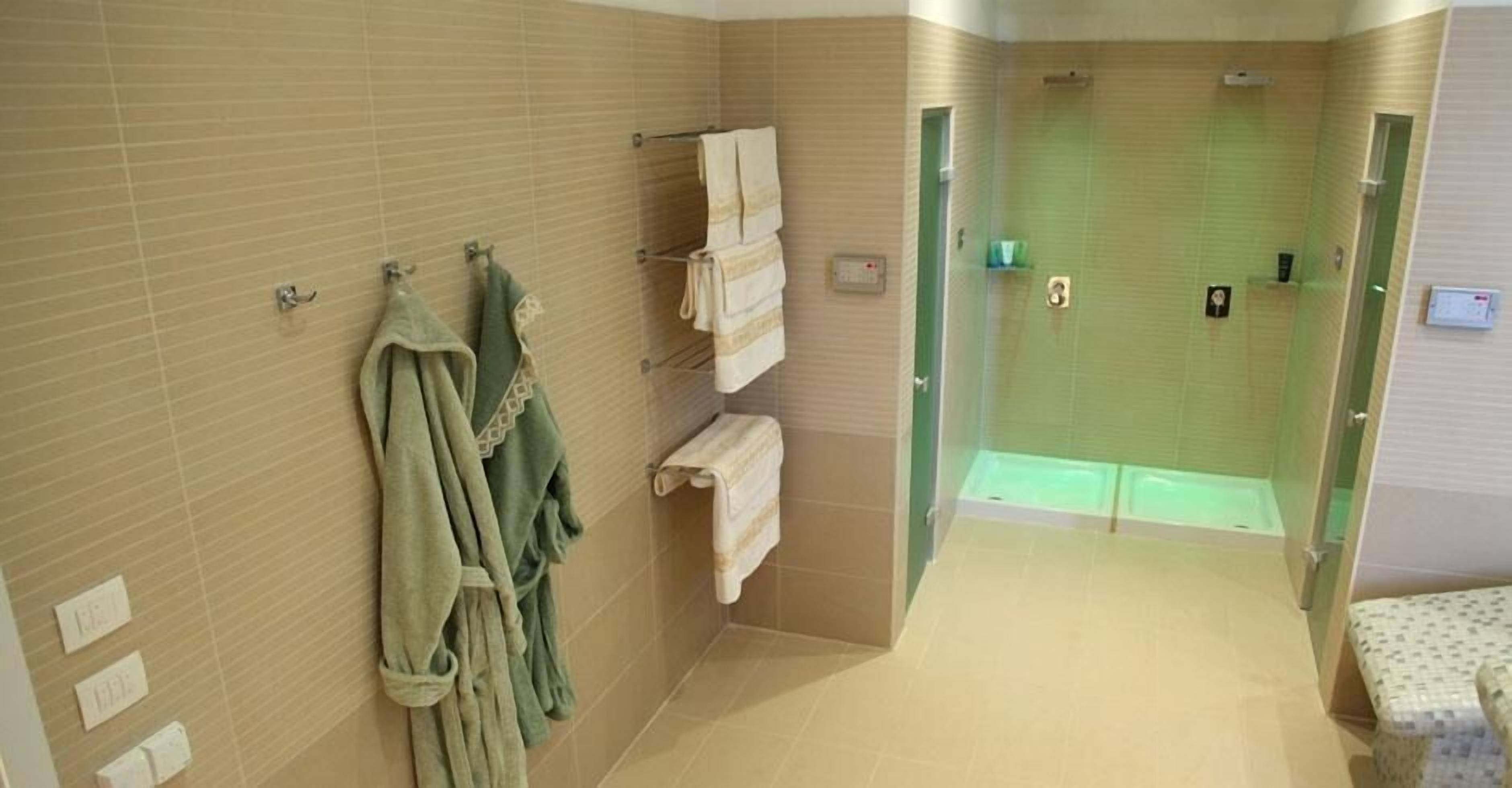 A modern bathroom with a shower, a glass-enclosed jacuzzi, and a towel rack with robes.