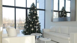 Un salon moderne avec un canapé blanc, une table basse blanche et un sapin de Noël.