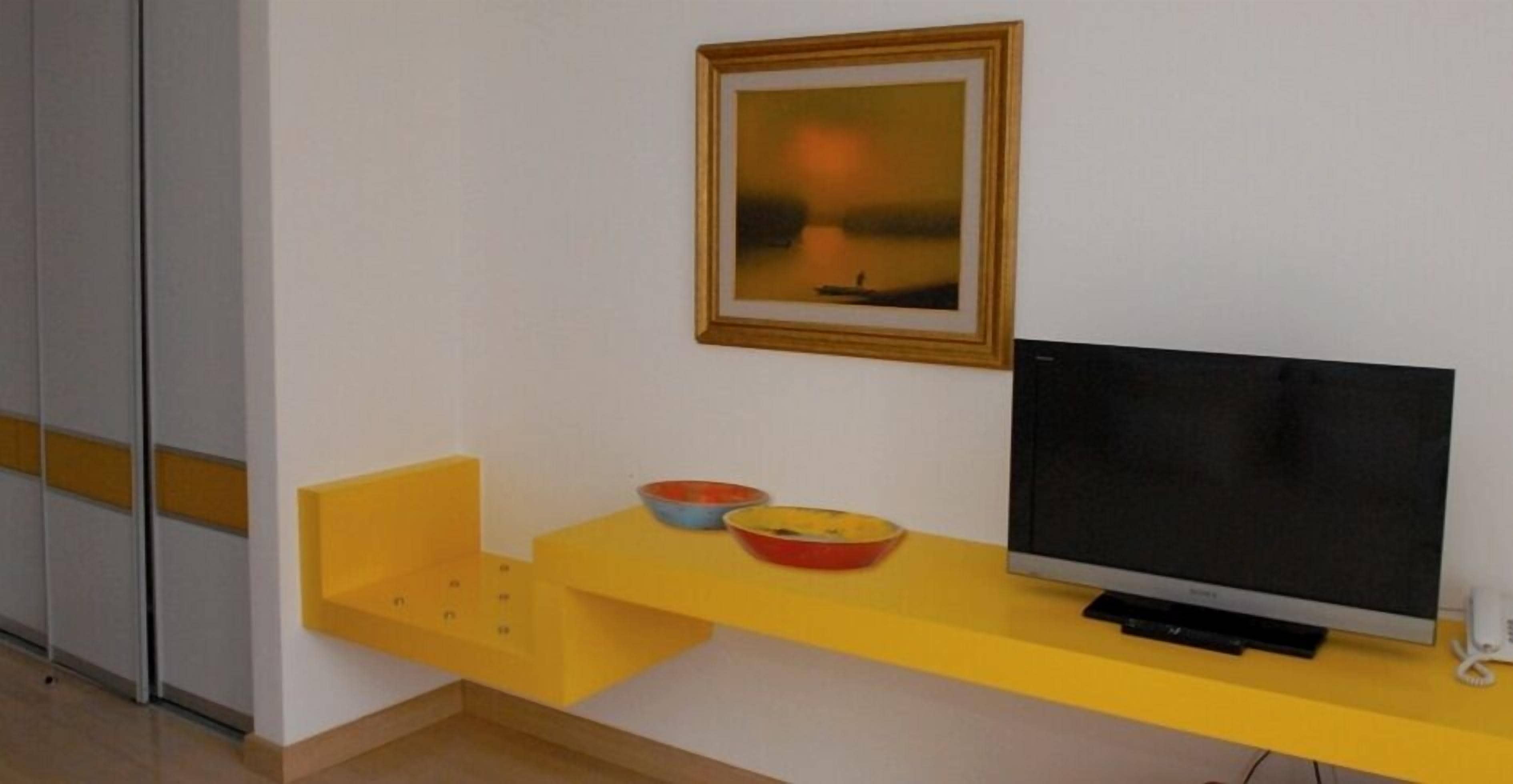 A room with a yellow TV stand, a flat-screen TV, and a framed picture on the wall.
