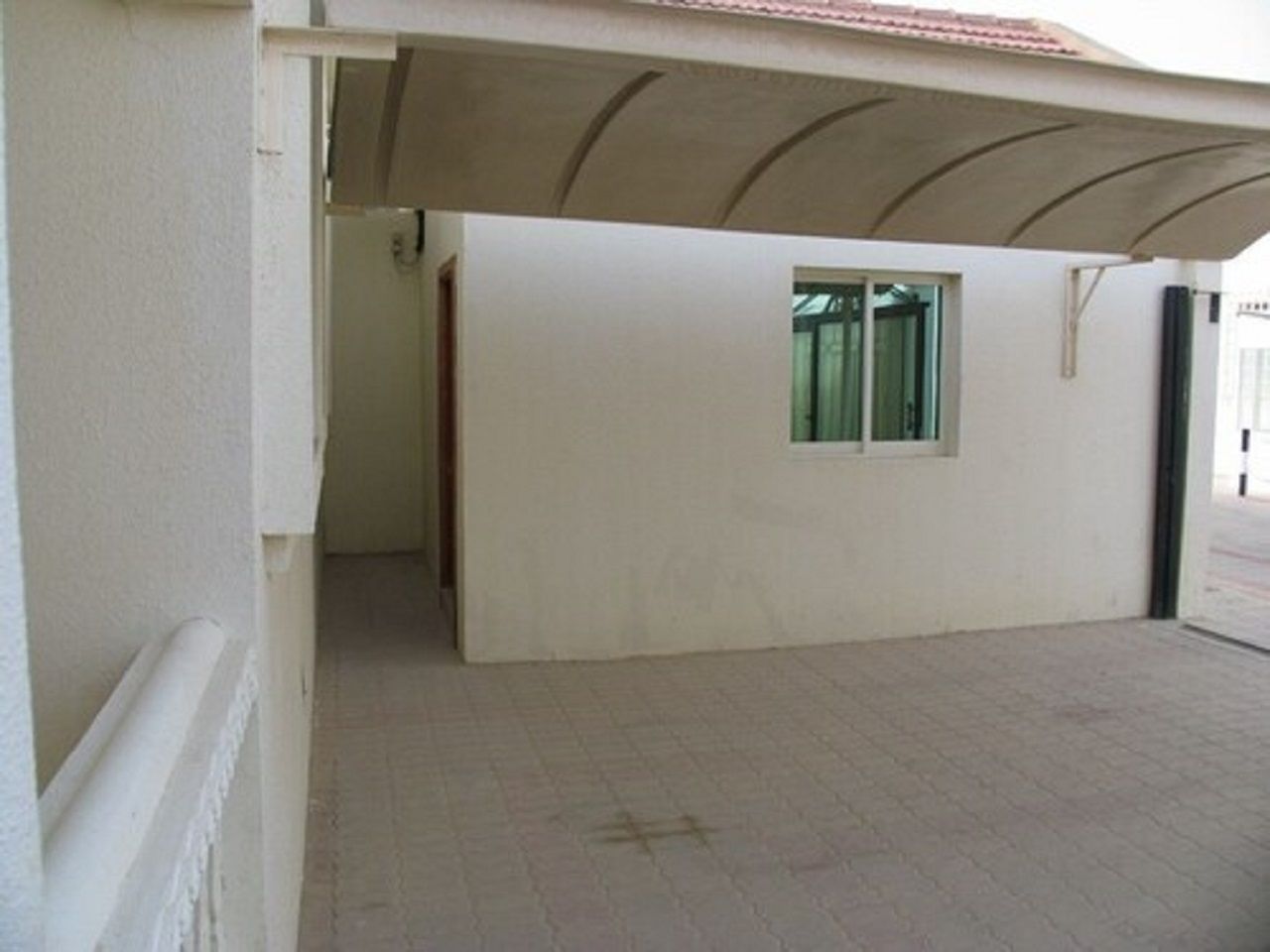 A corridor with a tiled floor leading to a room with a window.