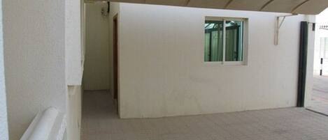 A corridor with a tiled floor leading to a room with a window.
