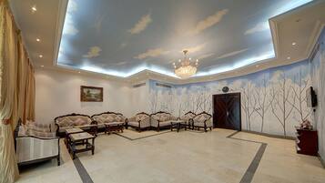 A spacious room with a high ceiling, a chandelier, and a seating area with sofas and a coffee table.