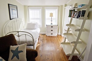 A bedroom with a bed, bedside table, lamp, and a bookshelf.