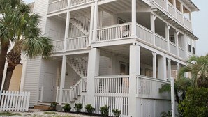 Un edificio blanco de varios pisos con balcones y una cerca blanca de piquetes.