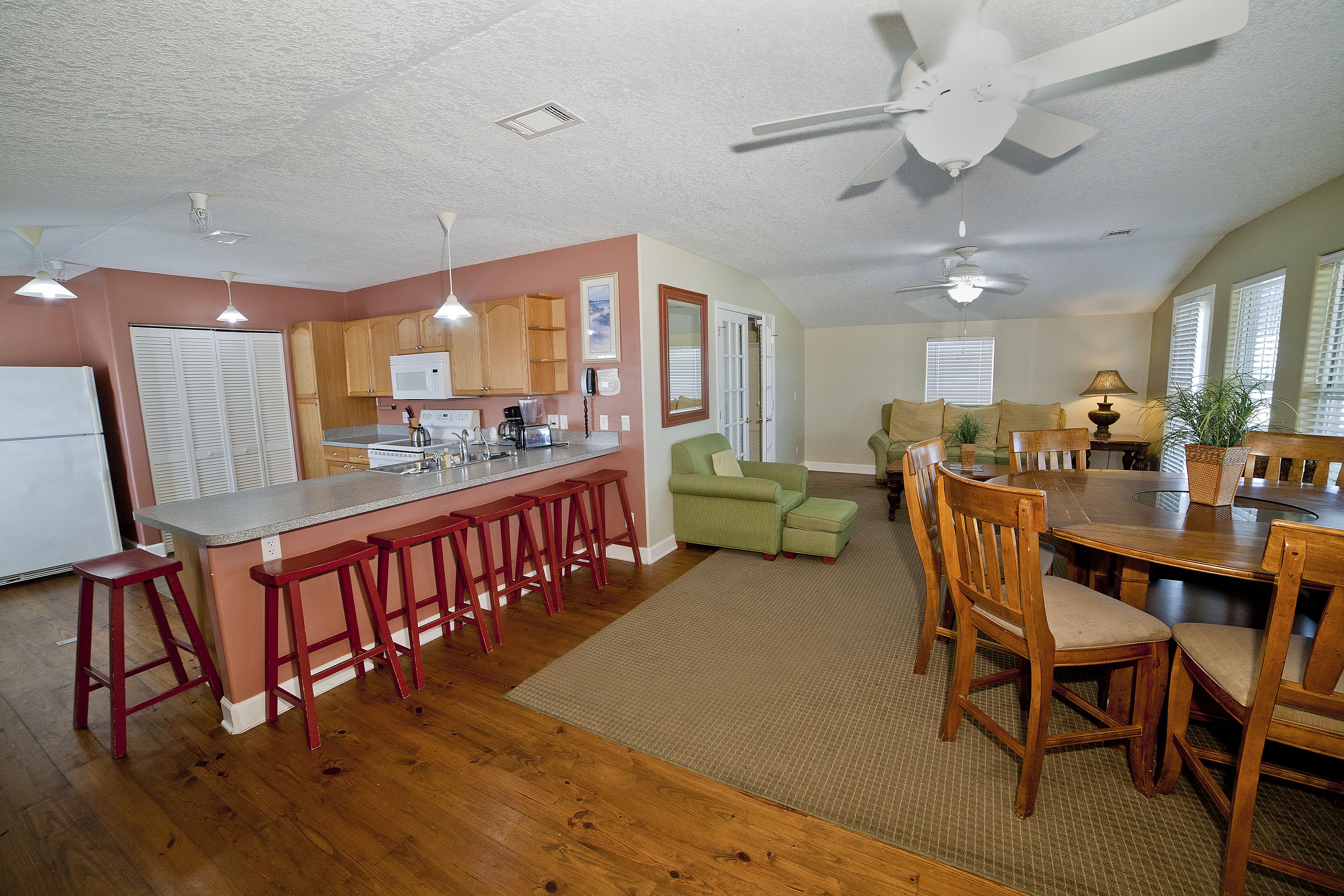 A spacious kitchen with wooden cabinets, a bar area with stools, and a dining table with chairs.