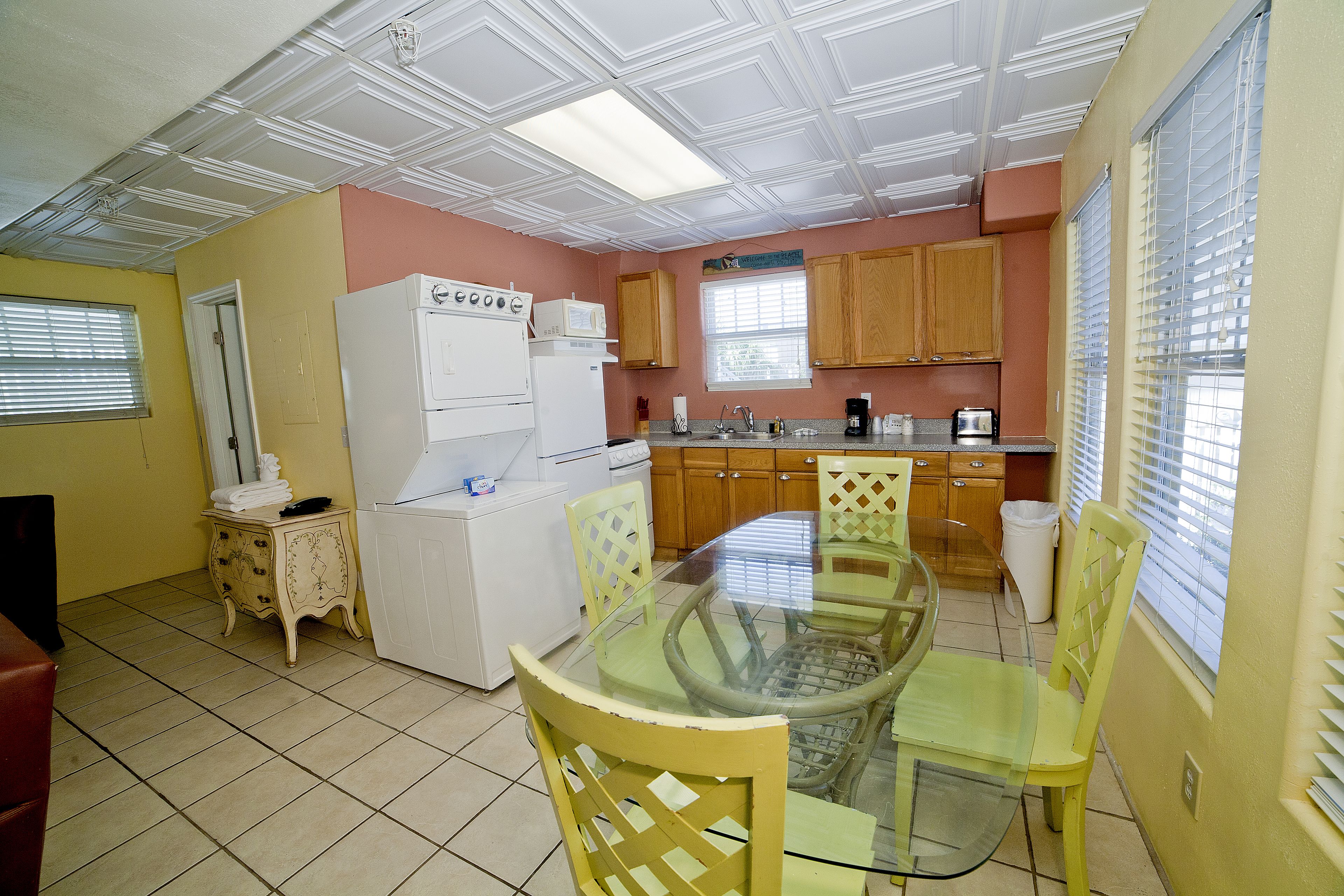 A compact kitchen with a dining area, featuring a refrigerator, stove, microwave, and wooden cabinets.