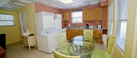 A compact kitchen with a dining area, featuring a refrigerator, stove, microwave, and wooden cabinets.