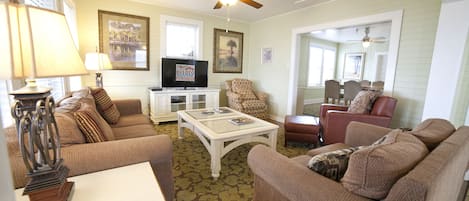 A living room with a ceiling fan, a television, and a dining area with a table and chairs.
