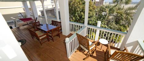 A wooden deck with a table and chairs, a red hammock, and a view of trees and buildings.