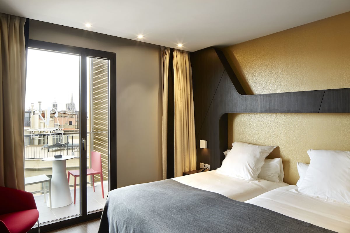A hotel room with a large bed, a desk, a chair, and a view of the cityscape.