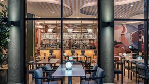 A modern restaurant with a bar area, multiple seating options, and a distinctive ceiling design. - Hotel Vincci Gala (Barcelona)