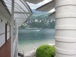 A view from a balcony overlooking a body of water with a mountainous backdrop.