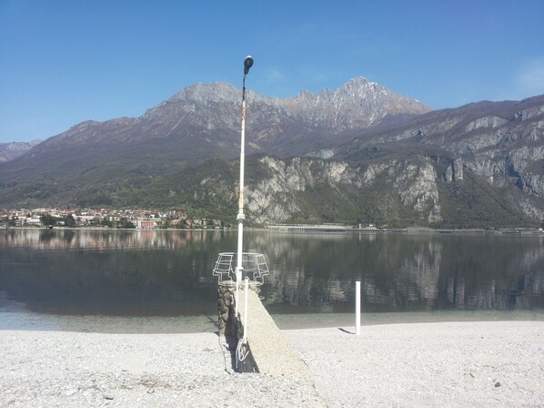 A lake with a mountain backdrop, a pier extending into the water, and a distant town.