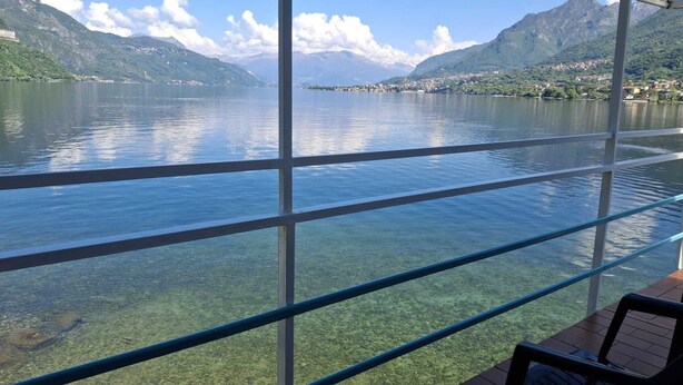 A clear view of a lake with mountains in the background, a wooden deck, and a metal railing. - Hotel Resort Nautilus (Mandello del Lario)