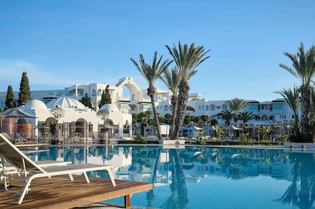 Una piscina al aire libre, sombrillas, sillones reclinables de piscina