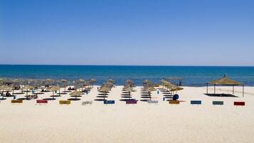 On the beach, white sand, sun-loungers, beach umbrellas