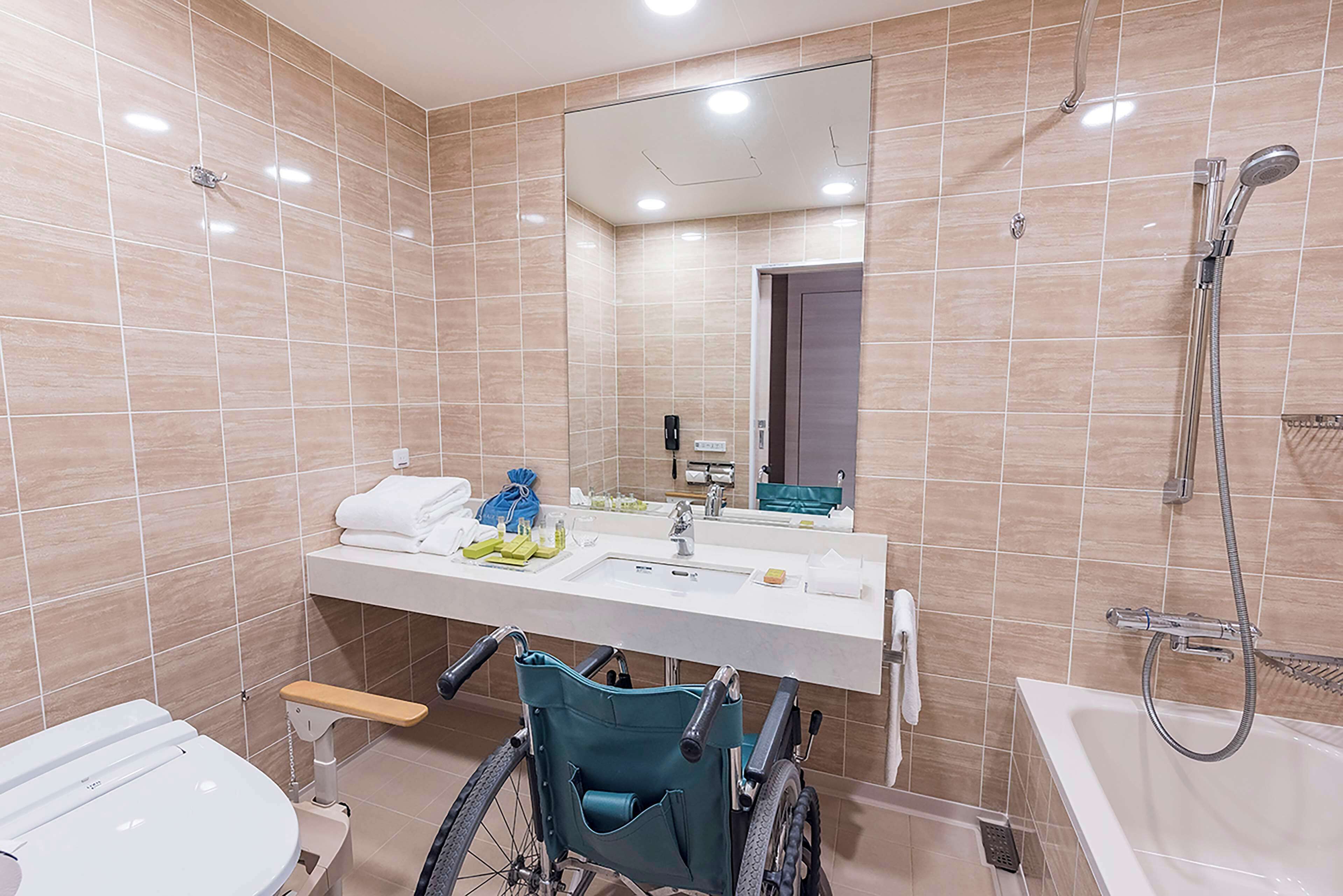 Une salle de bain moderne équipée d’un lavabo accessible aux personnes en fauteuil roulant, d’une baignoire et d’une douche.