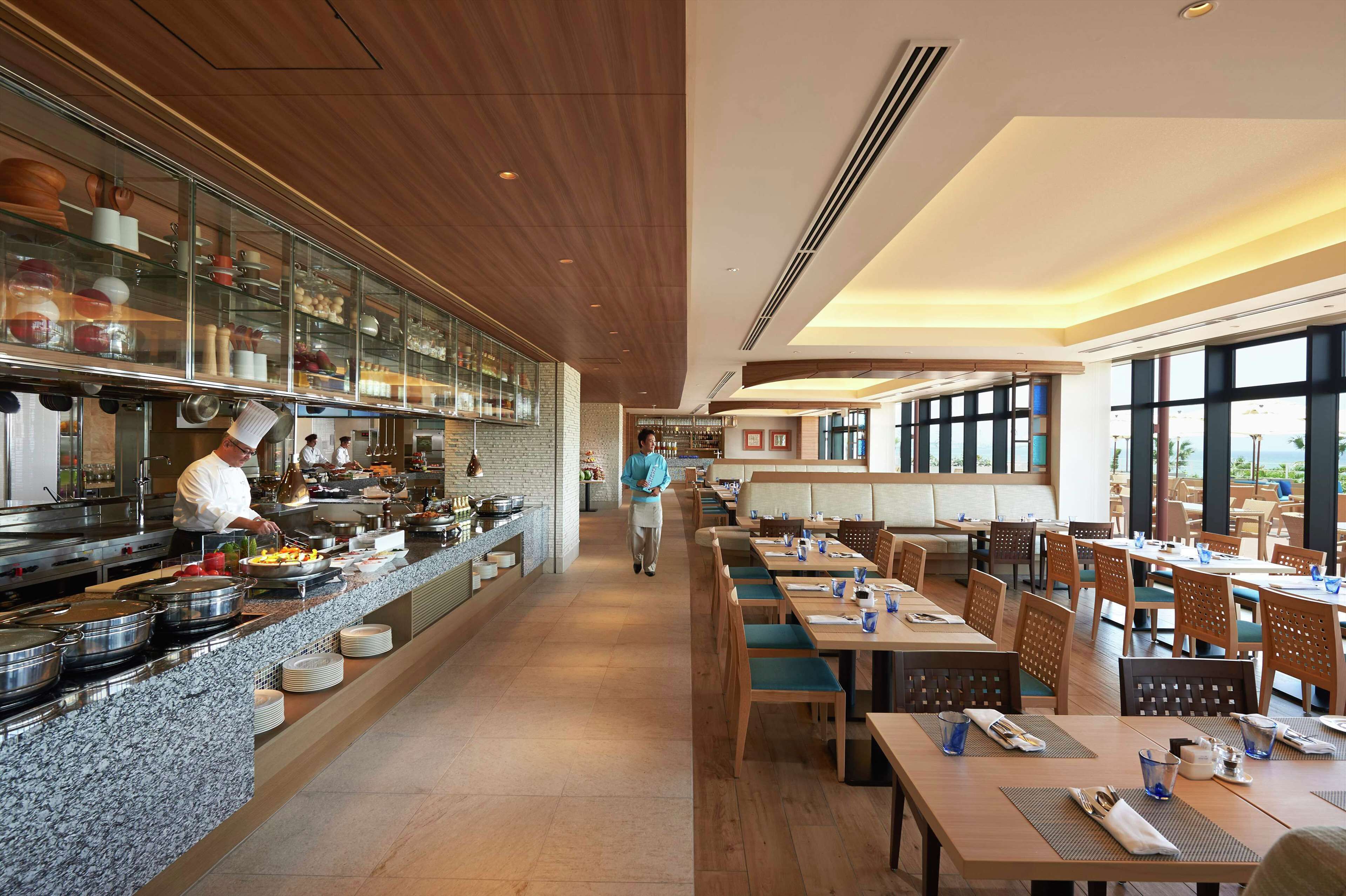 Un ristorante moderno con un lungo bancone, una sala da pranzo e una cucina.