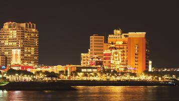 A waterfront hotel with multiple high-rise buildings, a marina, and a well-lit promenade.