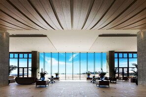 Un vestíbulo amplio con una gran vista a la playa, muebles modernos y techo de madera.