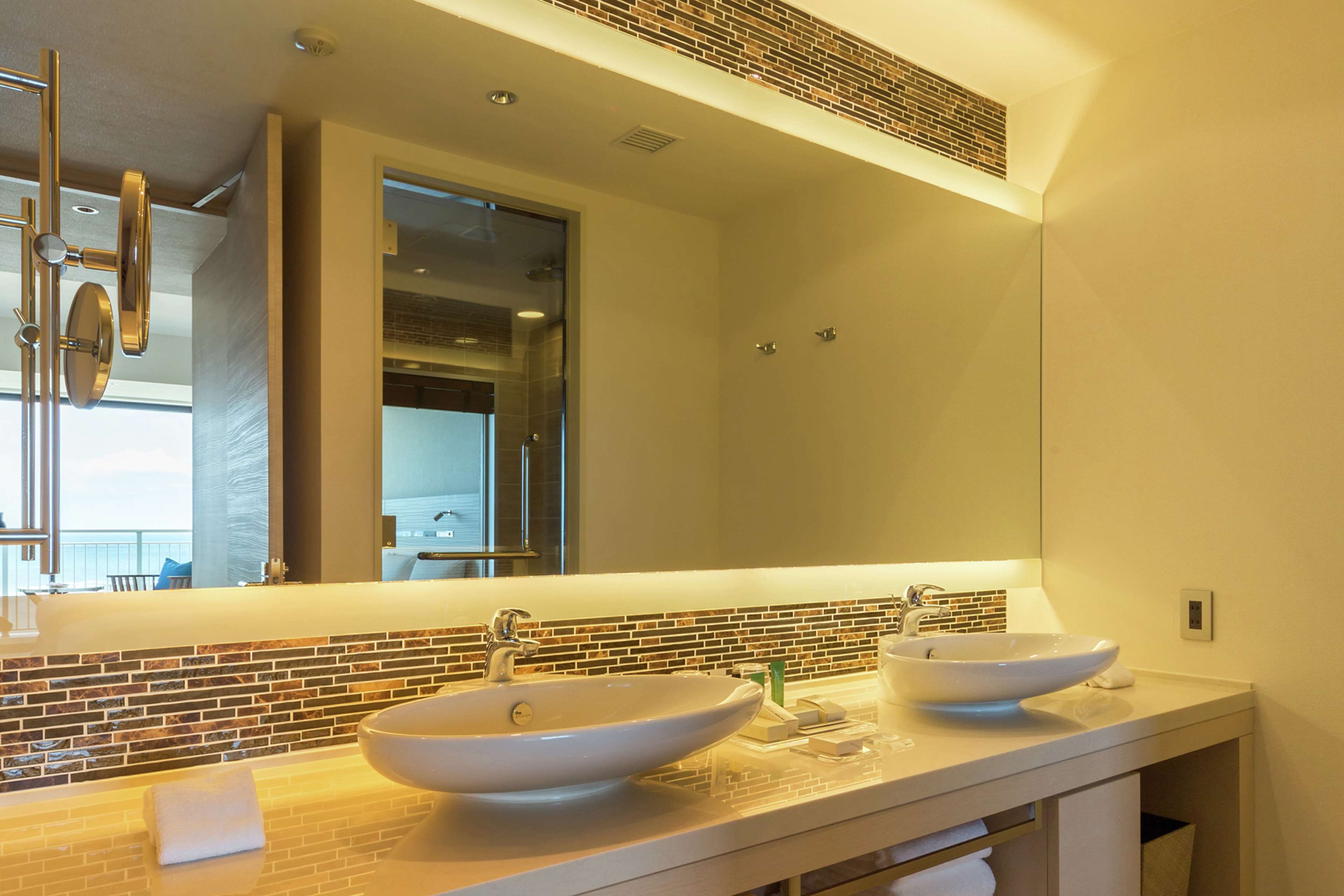 A modern bathroom with two vessel sinks, a large mirror, and a tiled backsplash.