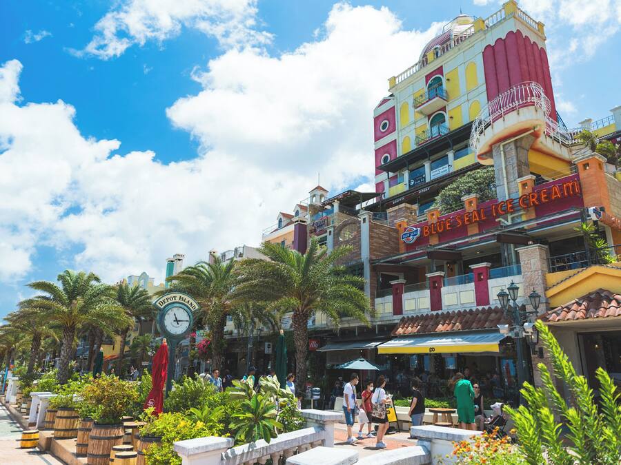 Un edificio colorido con un reloj, palmeras y un letrero que dice 'Blue Seal Ice Cream'.