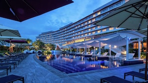 Um hotel com piscina, área de estar externa e guarda-sóis.
