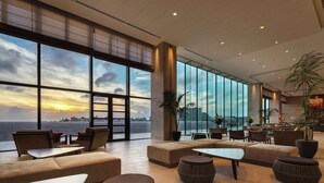 Um hall amplo com janelas grandes, assentos confortáveis e vista para o pôr do sol sobre a água.