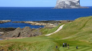 Camp de golf amb vistes a l'oceà i una gran formació rocosa.