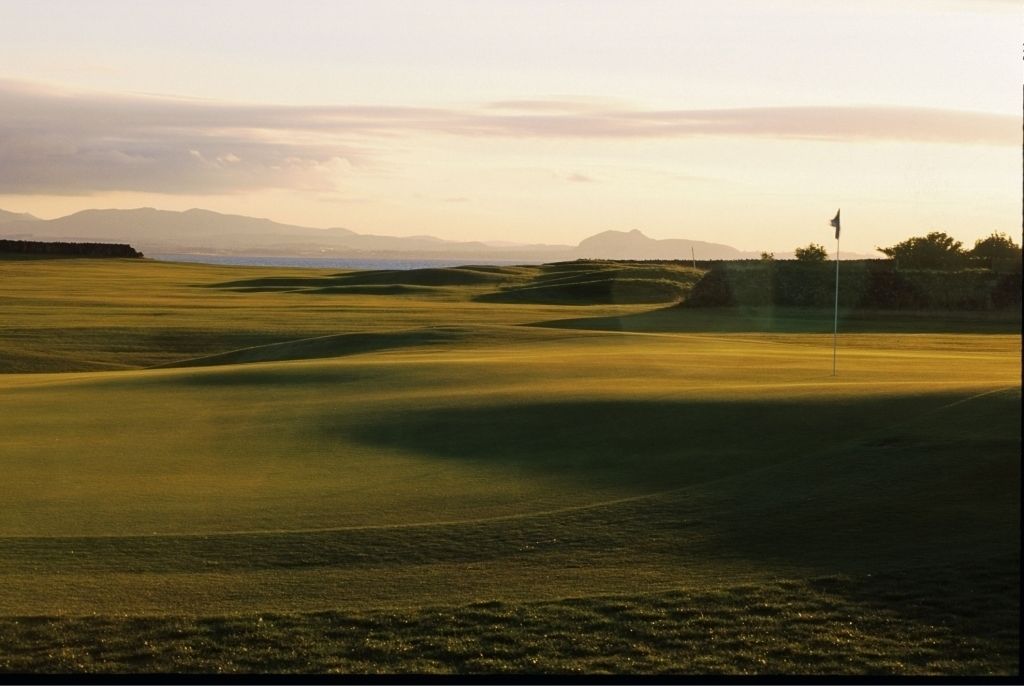 A golf course with rolling hills and a flag on a flagstick.