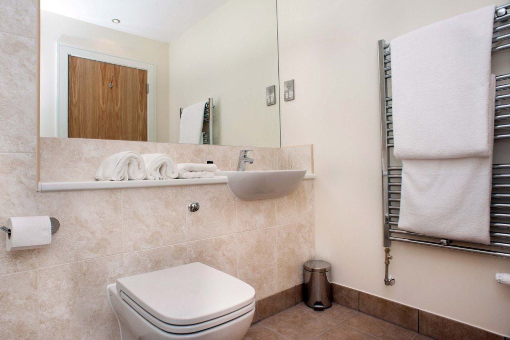 A modern bathroom with a toilet, sink, and towel rack.