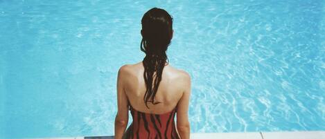 Una persona sentada al borde de una piscina.