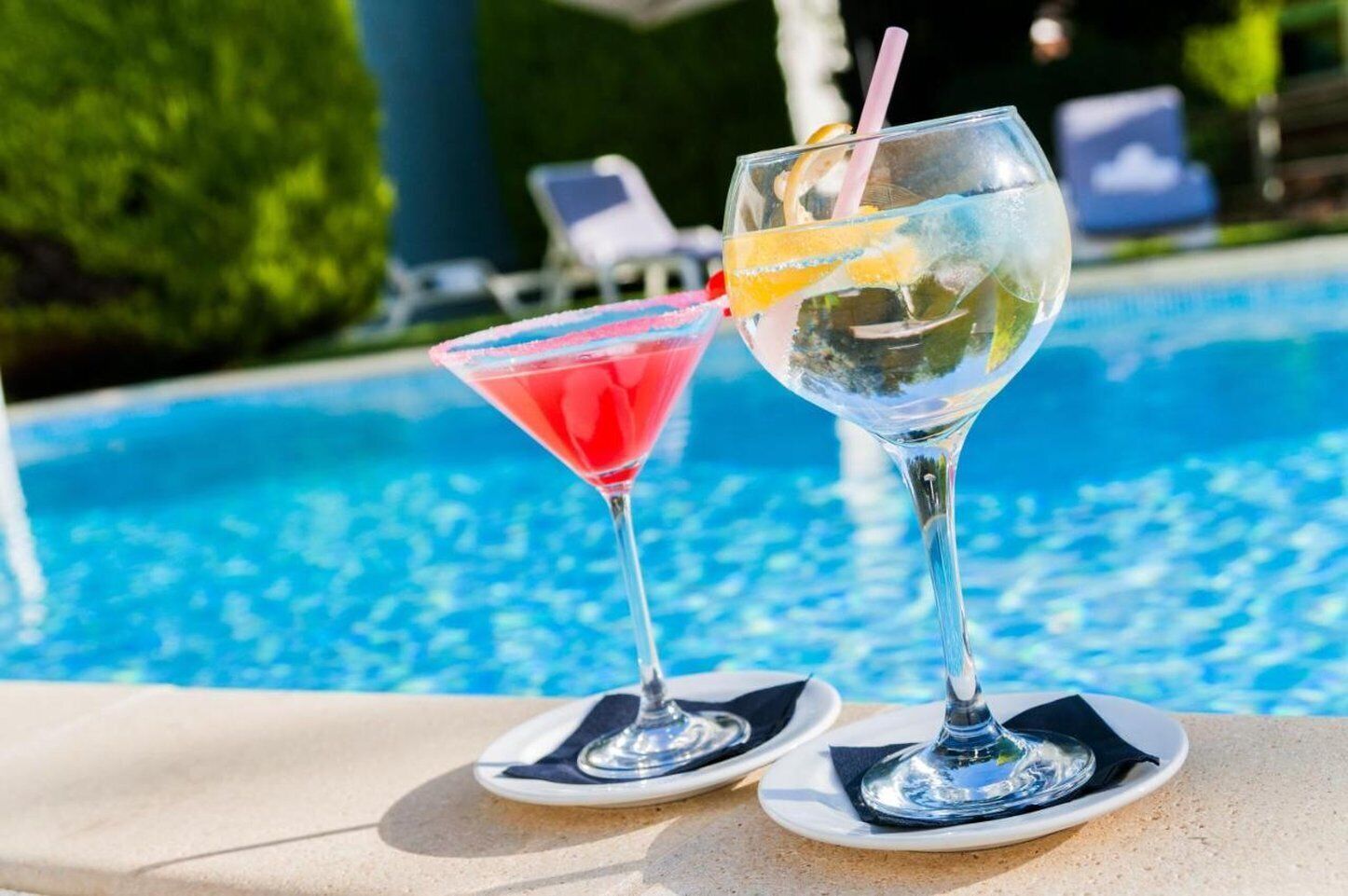 Deux cocktails sur une table au bord de la piscine, avec la piscine en arrière-plan.