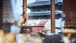 A person seated at a table with a view of traditional architecture through large windows. - JW Marriott Dongdaemun Square Seoul (Seoul)