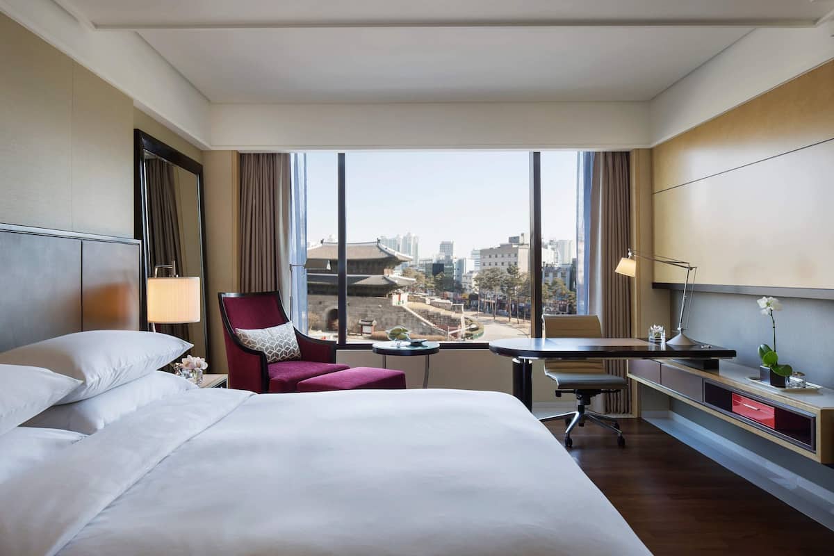 Une chambre d’hôtel avec un grand lit, un bureau, une chaise et une vue sur la ville.