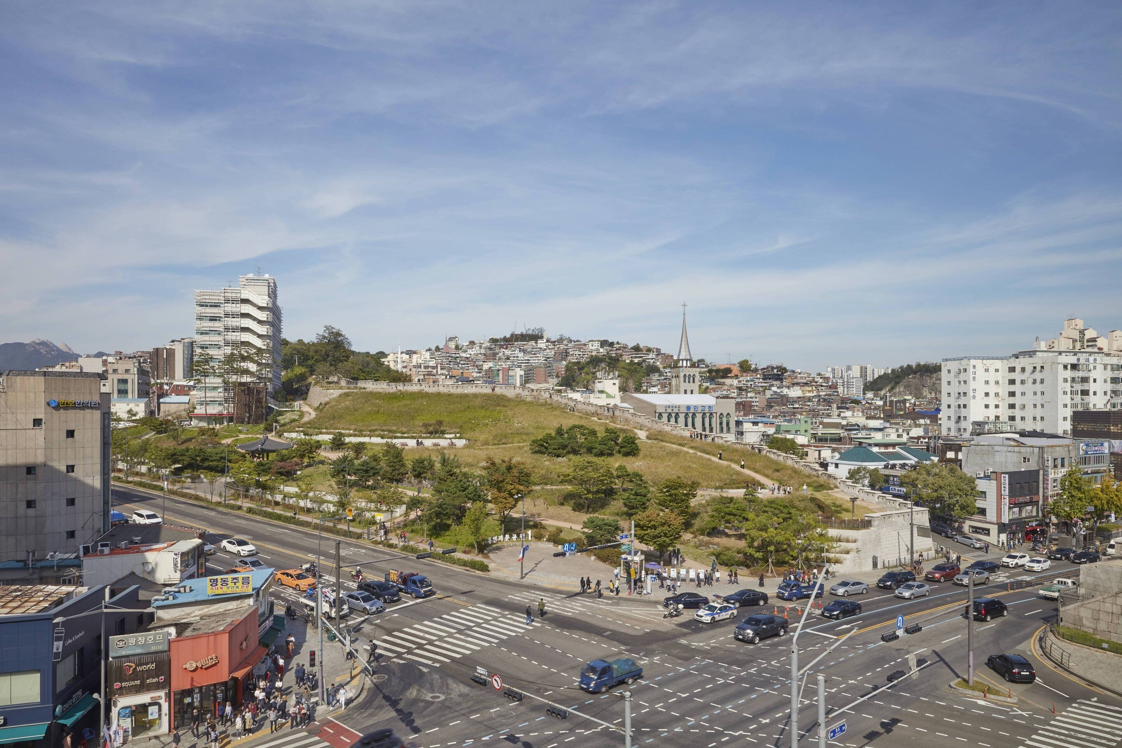 Un paisaje urbano con una colina destacada, edificios y una intersección con mucho tráfico.