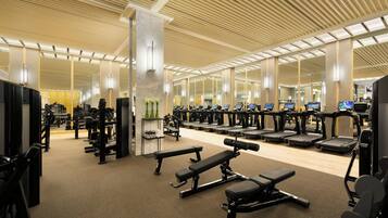 A gym with various exercise equipment, including treadmills, weight machines, and benches.