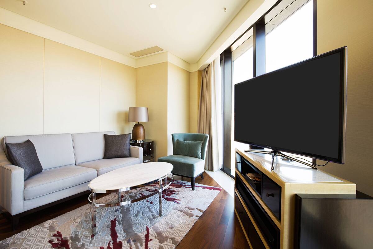 Un salon moderne comprenant un canapé, un fauteuil, une table basse et un téléviseur à écran plat.