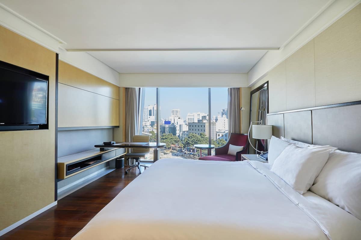 Une chambre d’hôtel avec un grand lit, un téléviseur fixé au mur, un bureau et une chaise.
