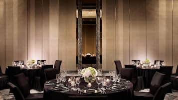 Un comedor elegante con mesas redondas, manteles negros y centros de mesa con flores blancas.