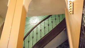 Uma escadaria com corrimão verde e um candelabro com várias lâmpadas.