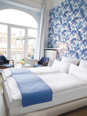 A hotel room with a large bed, two chairs, a small table, and a view of the city through large windows. - Fritz im Pyjama (Hamburg)