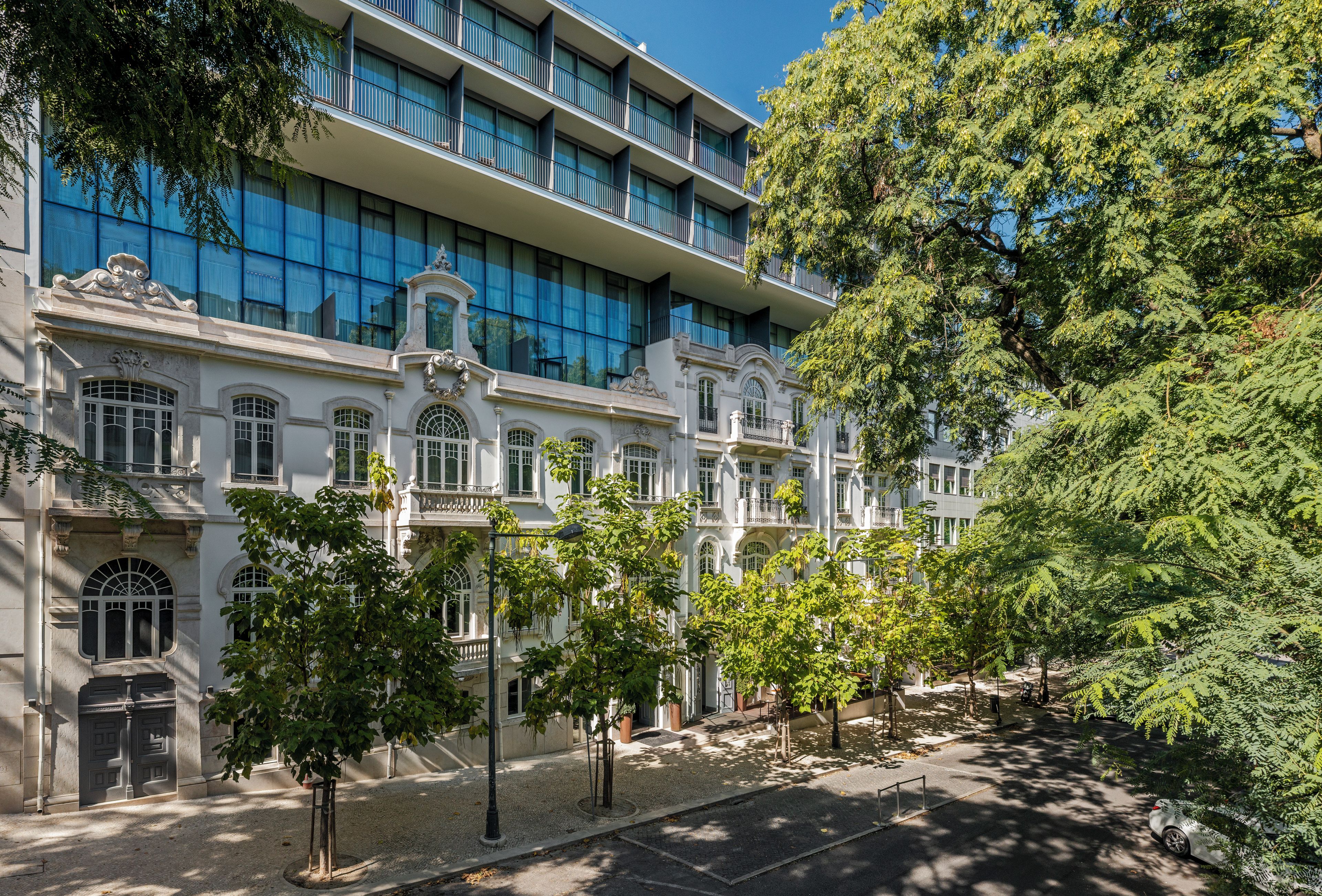 A multi-story building with a classical facade, large windows, and a courtyard with trees.