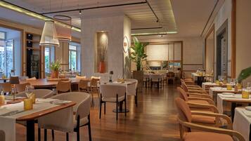 A spacious restaurant with multiple dining areas, wooden flooring, and modern lighting fixtures.