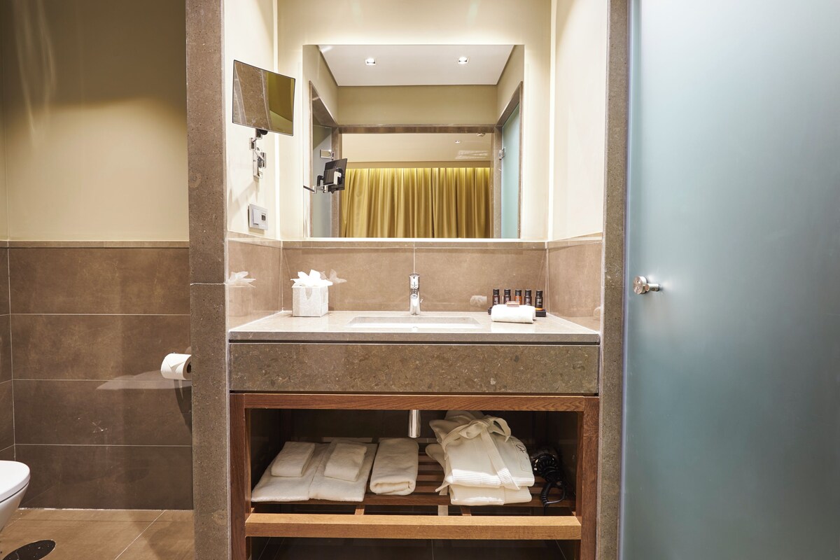 A bathroom with a sink, mirror, towel rack, and a shower curtain.