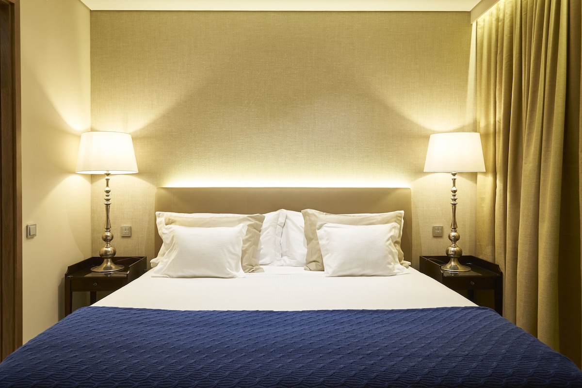 A hotel room with a large bed, two bedside tables, and a headboard.