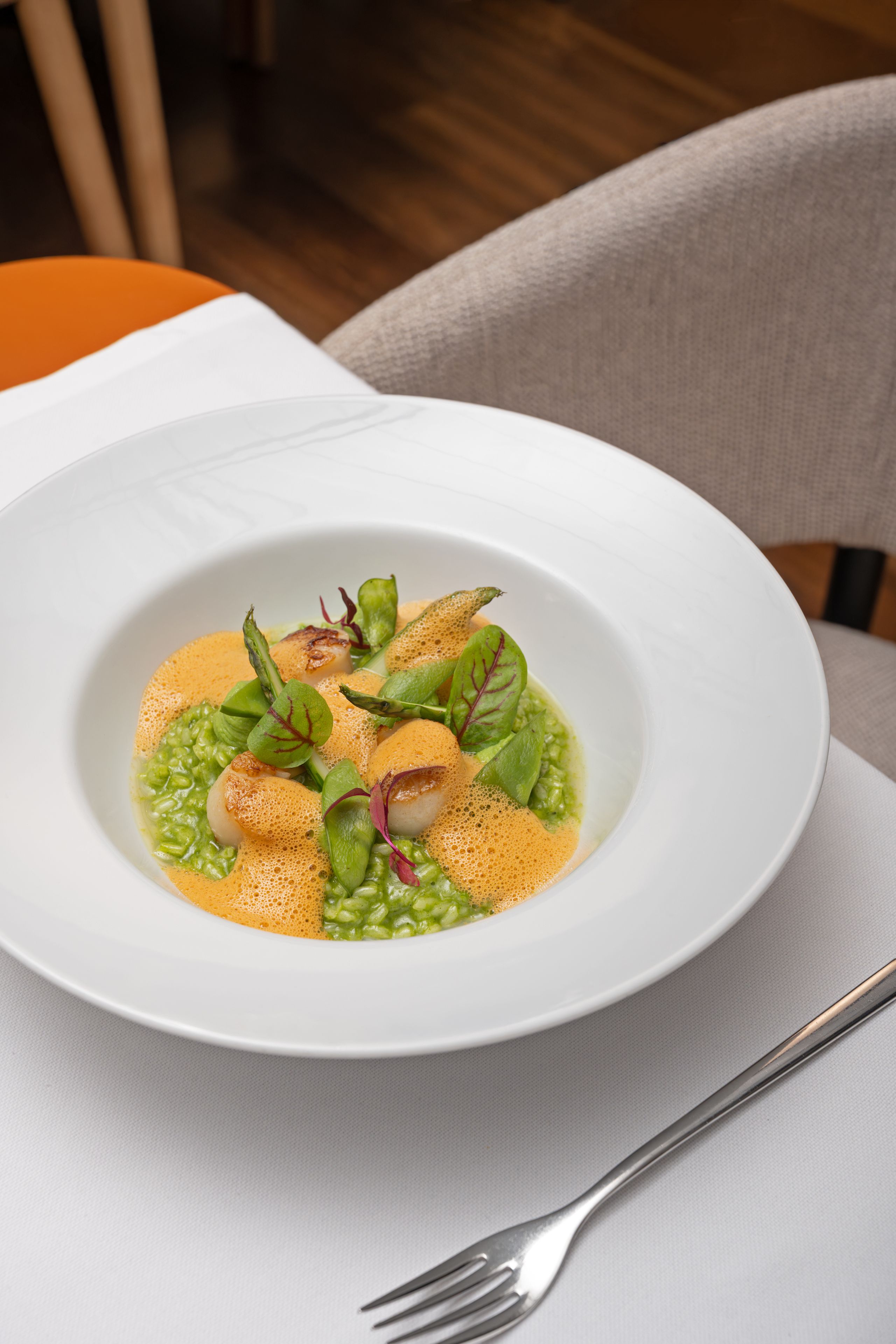 A white plate with a dish of food, a fork, and a napkin on a table.