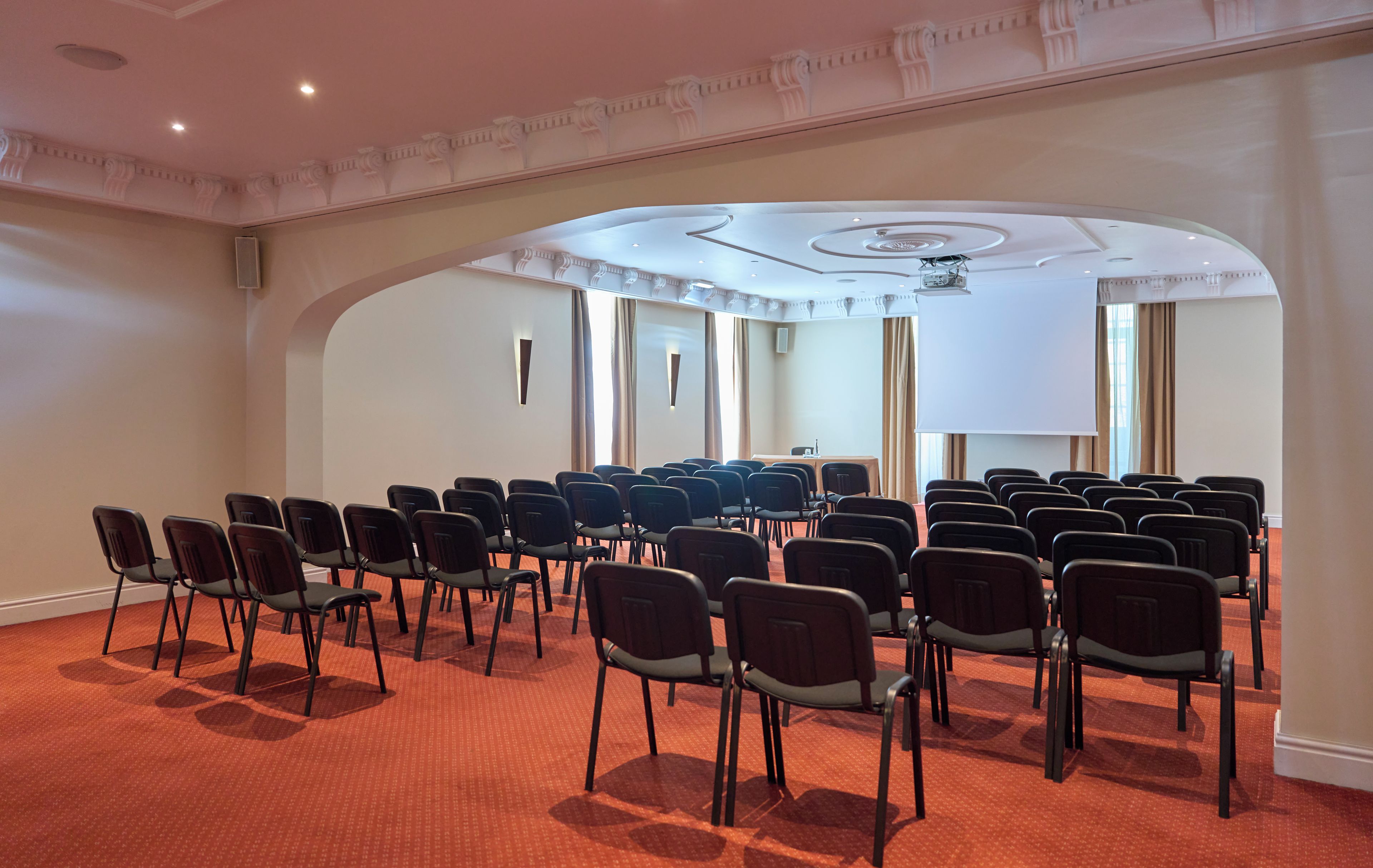 Un salón de conferencias con filas de sillas, una pantalla grande y un techo con diseño circular.