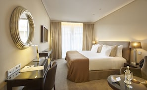 A hotel room with a bed, desk, chair, and a large mirror. - PortoBay Liberdade (Lisbon)